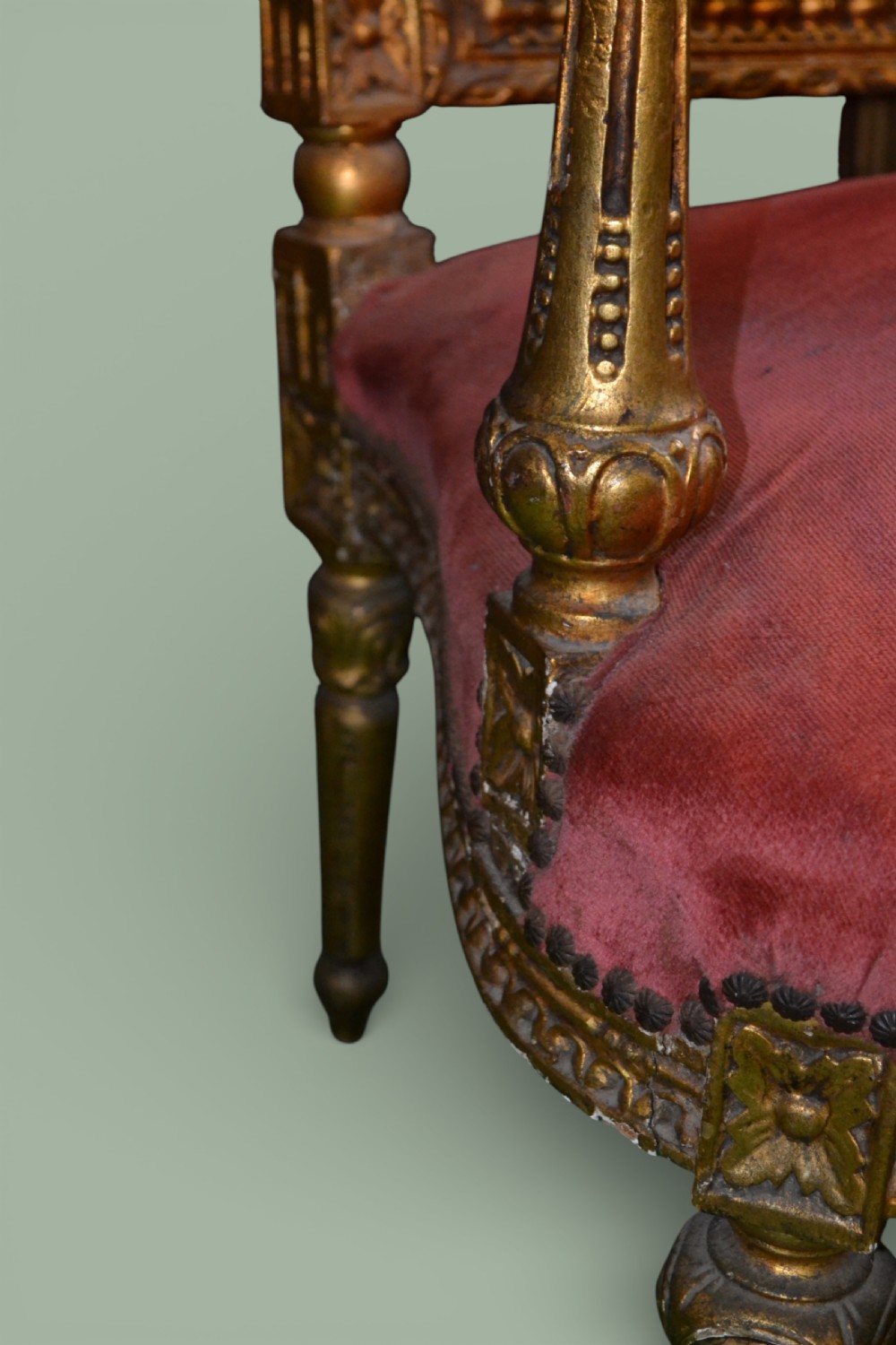 A pair of French giltwood armchairs featuring carved gold leaf frames, button-tufted red velvet backrests, padded armrests, and fluted turned legs. View VI