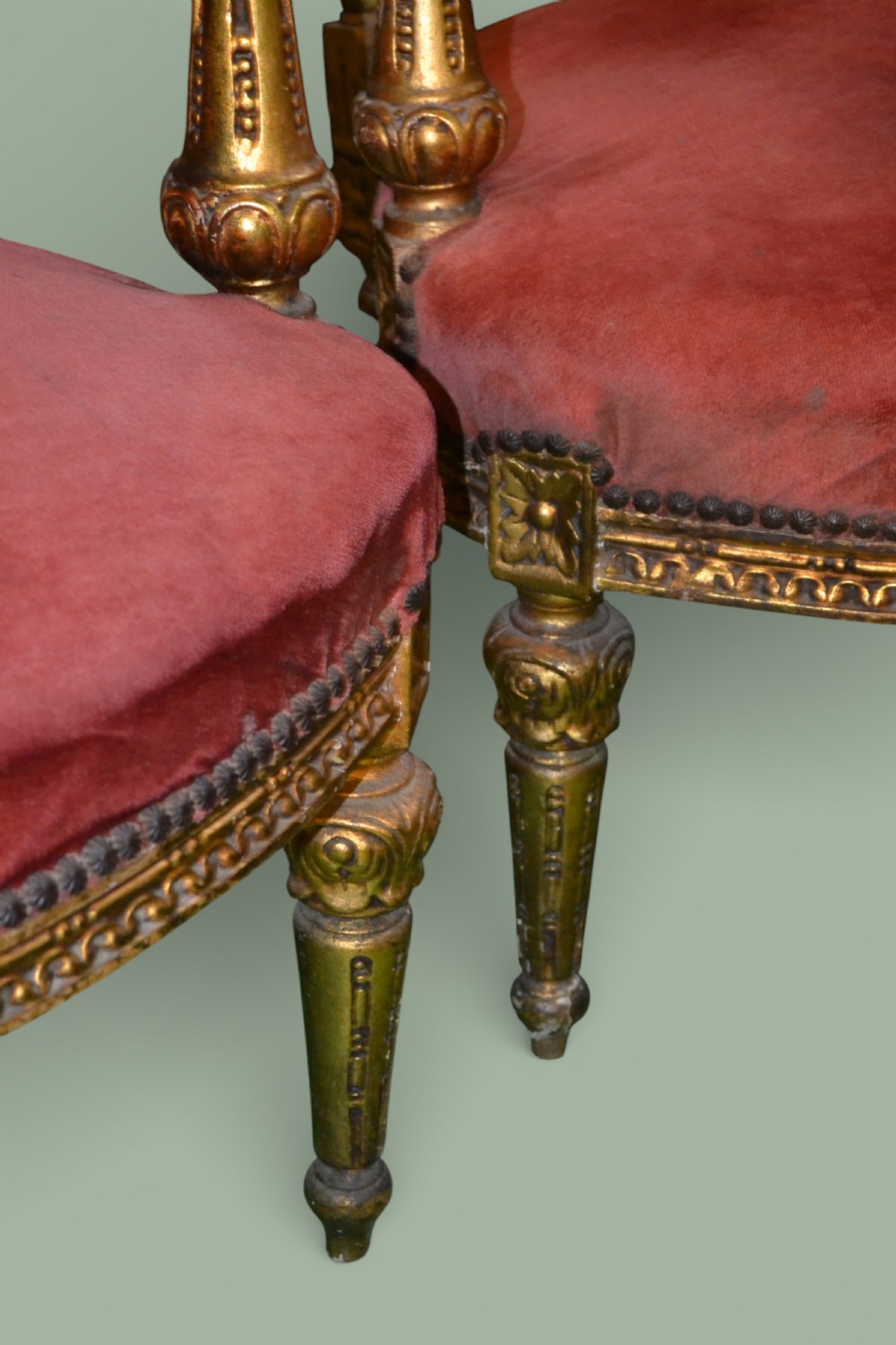 A pair of French giltwood armchairs featuring carved gold leaf frames, button-tufted red velvet backrests, padded armrests, and fluted turned legs. View VII