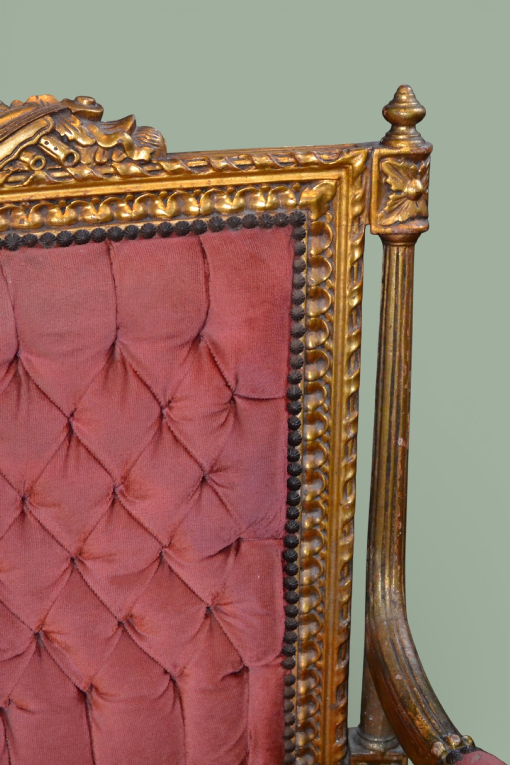 A pair of French giltwood armchairs featuring carved gold leaf frames, button-tufted red velvet backrests, padded armrests, and fluted turned legs. View IX