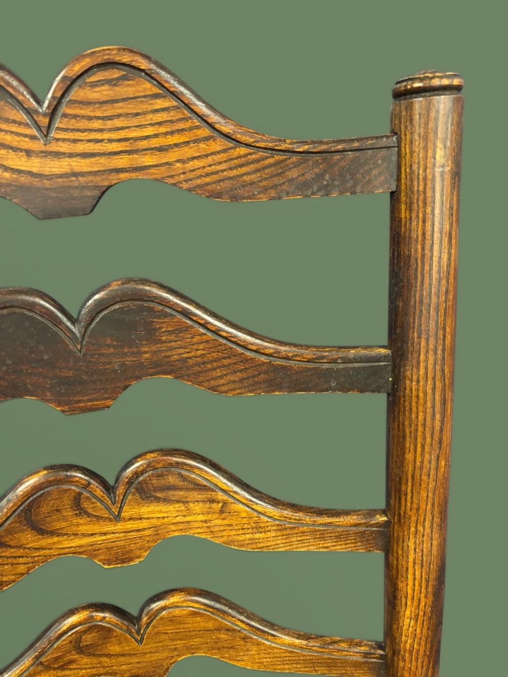 An antique elm ladderback armchair featuring six shaped horizontal slats, curved armrests, and a woven rush seat. View VIII