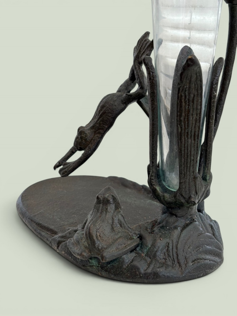 A dark patinated bronze Art Nouveau flower holder featuring sculpted frogs around a lily stem with a clear fluted glass vase liner. View II