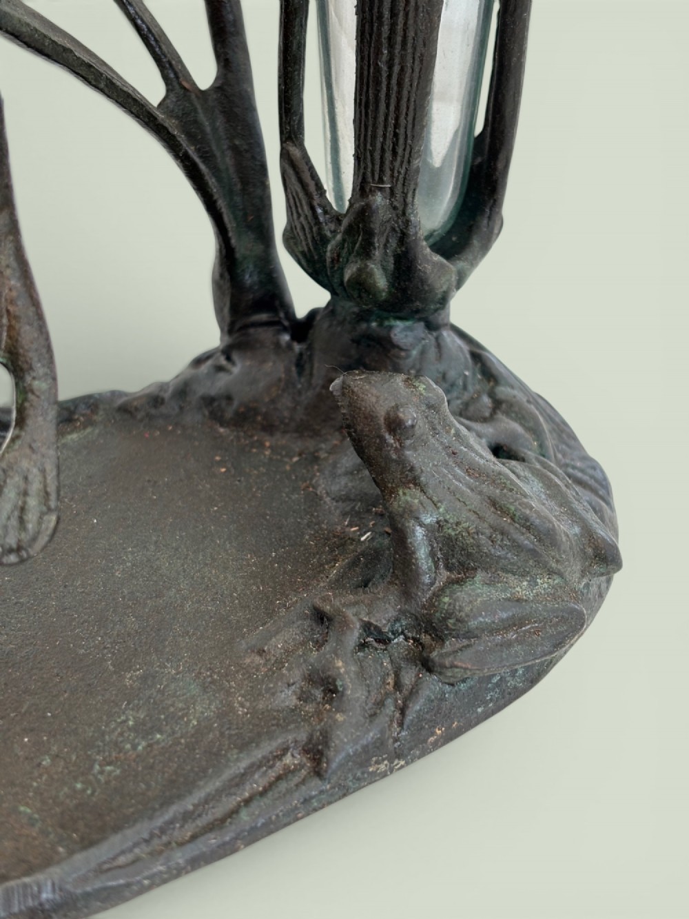 A dark patinated bronze Art Nouveau flower holder featuring sculpted frogs around a lily stem with a clear fluted glass vase liner. View V