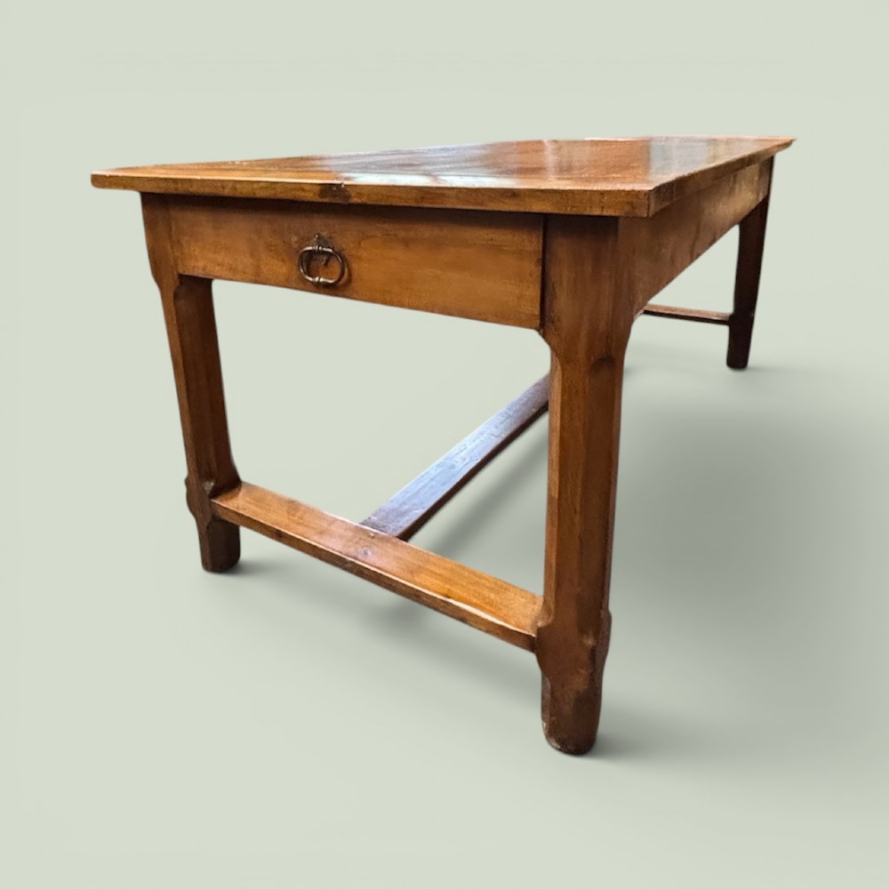 A 19th-century French cherrywood farmhouse table featuring two drawers with iron ring pulls and a sturdy H-stretcher base.