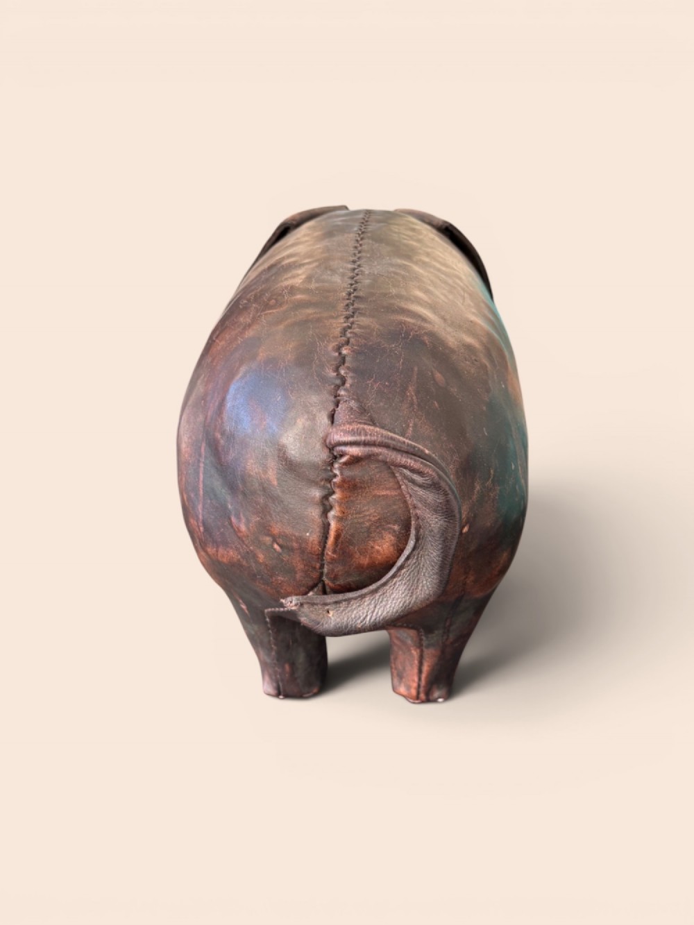 A handcrafted dark brown leather footstool shaped in the form of a pig with stitched panel detailing. View III