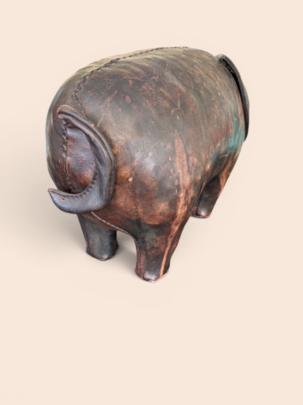 A handcrafted dark brown leather footstool shaped in the form of a pig with stitched panel detailing. View IV