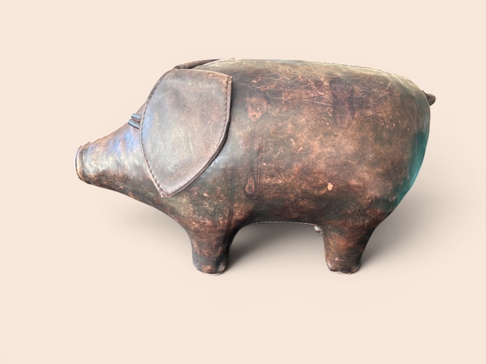 A handcrafted dark brown leather footstool shaped in the form of a pig with stitched panel detailing. View V