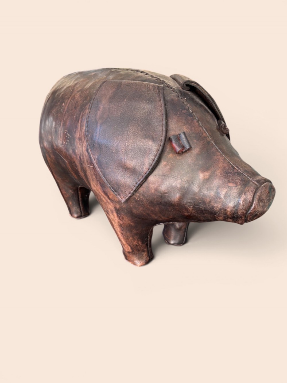 A handcrafted dark brown leather footstool shaped in the form of a pig with stitched panel detailing. View VII