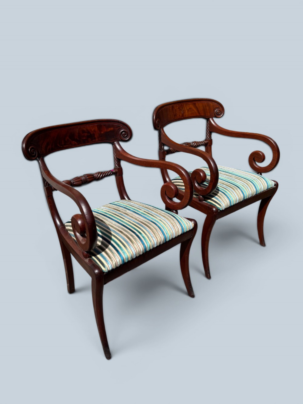 A pair of antique Regency mahogany armchairs featuring curved scroll arms, striped velvet seats, and sabre legs. View II