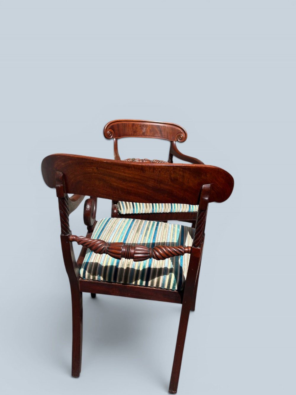 A pair of antique Regency mahogany armchairs featuring curved scroll arms, striped velvet seats, and sabre legs. View IV