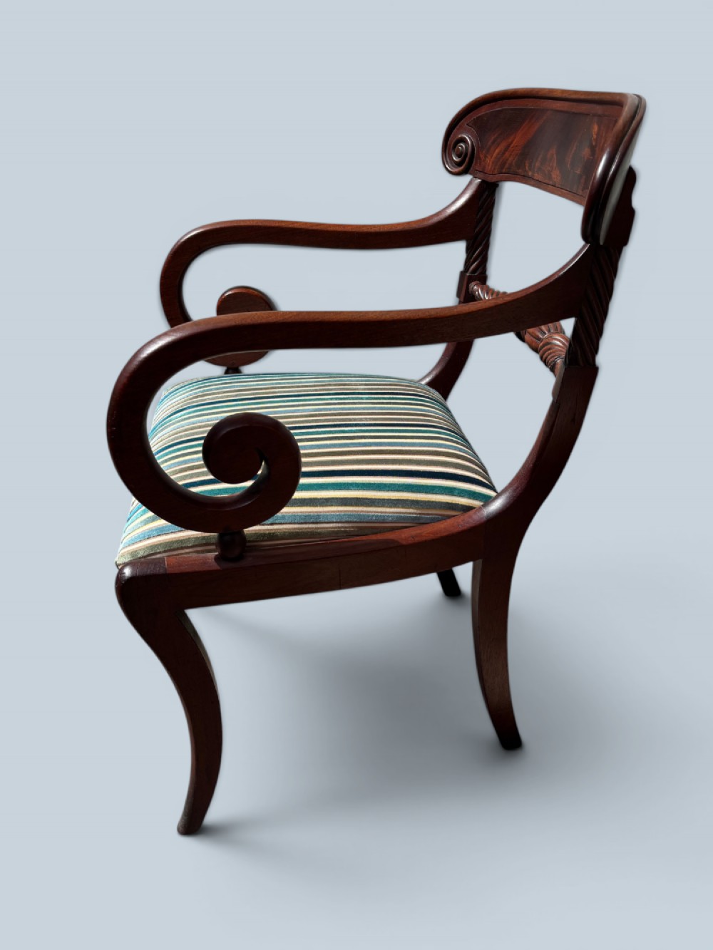 A pair of antique Regency mahogany armchairs featuring curved scroll arms, striped velvet seats, and sabre legs. View VI