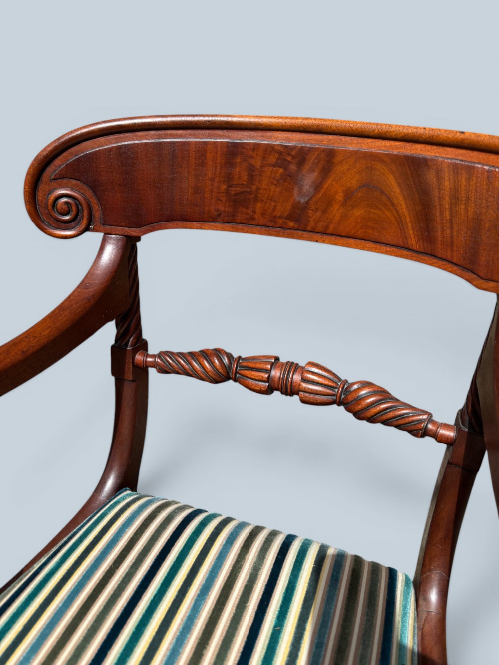 A pair of antique Regency mahogany armchairs featuring curved scroll arms, striped velvet seats, and sabre legs. View VII