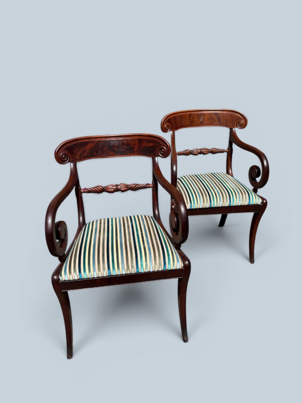 A pair of antique Regency mahogany armchairs featuring curved scroll arms, striped velvet seats, and sabre legs. View VIII
