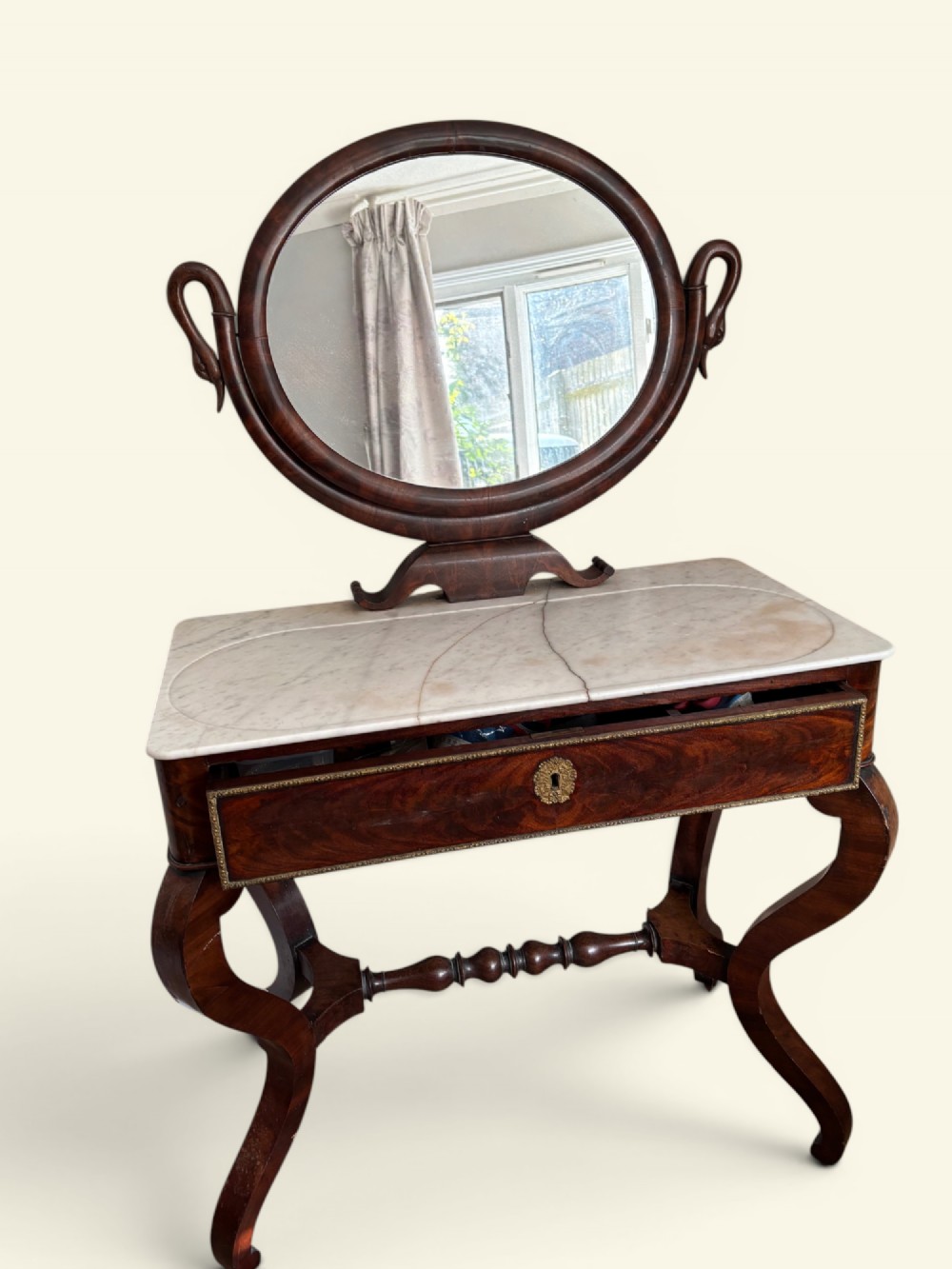 An antique dark wood dressing table featuring a swivel oval mirror, a white marble surface, S-curved legs on casters, and a central drawer. View II