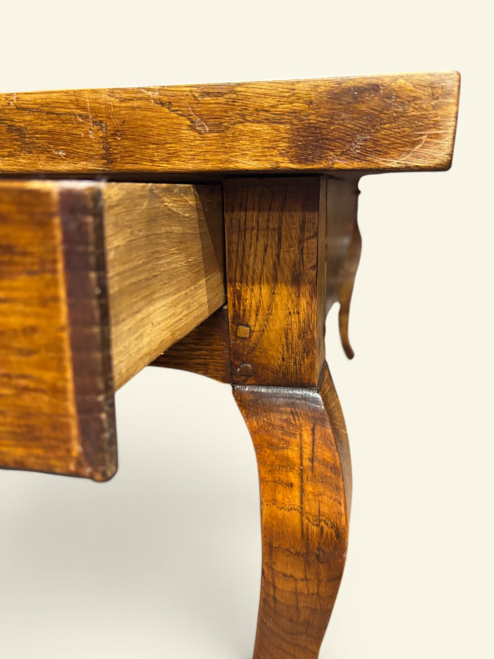 A long French farmhouse fruitwood dining table featuring curved cabriole legs, a scalloped apron, and an end drawer with an iron pull handle. View IV