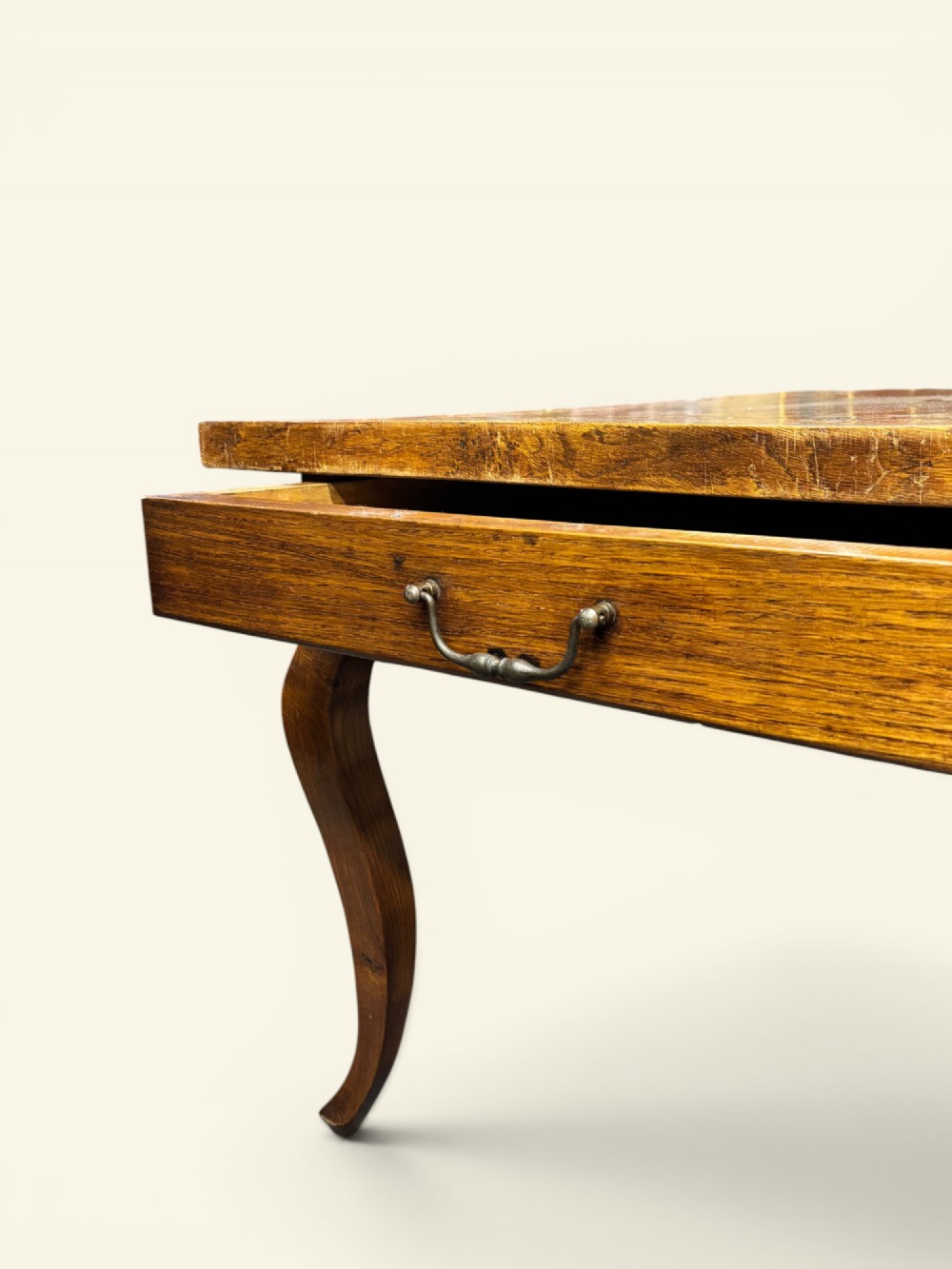 A long French farmhouse fruitwood dining table featuring curved cabriole legs, a scalloped apron, and an end drawer with an iron pull handle. View V