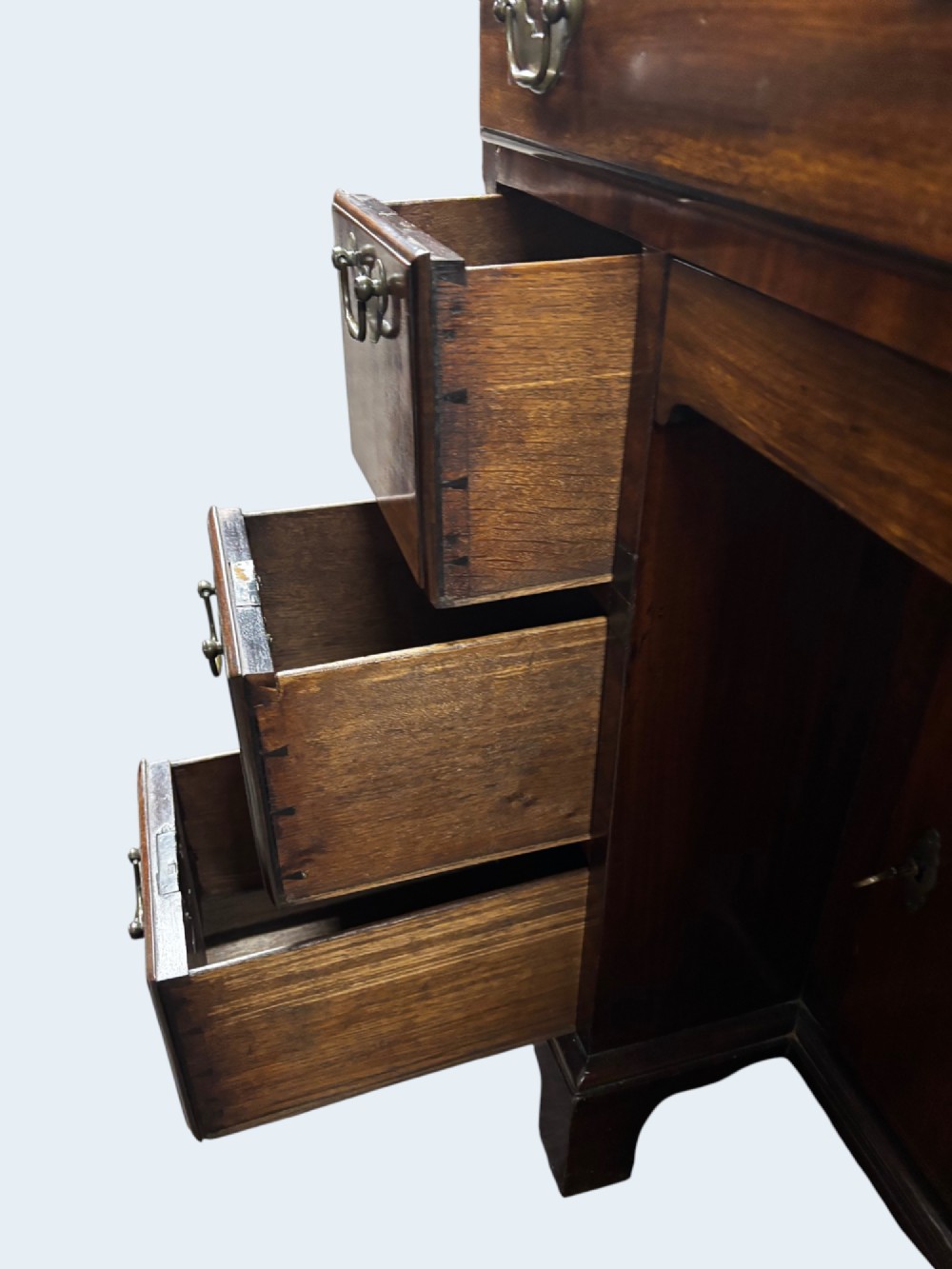A Georgian mahogany kneehole desk with multiple drawers, brass swan-neck handles, a central recessed cupboard, and bracket feet. View IV