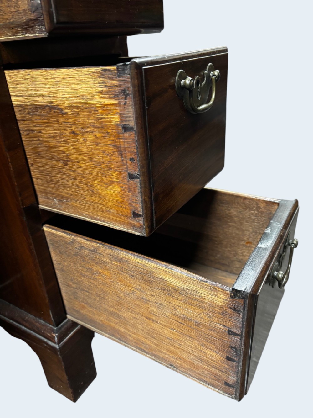 A Georgian mahogany kneehole desk with multiple drawers, brass swan-neck handles, a central recessed cupboard, and bracket feet. View V