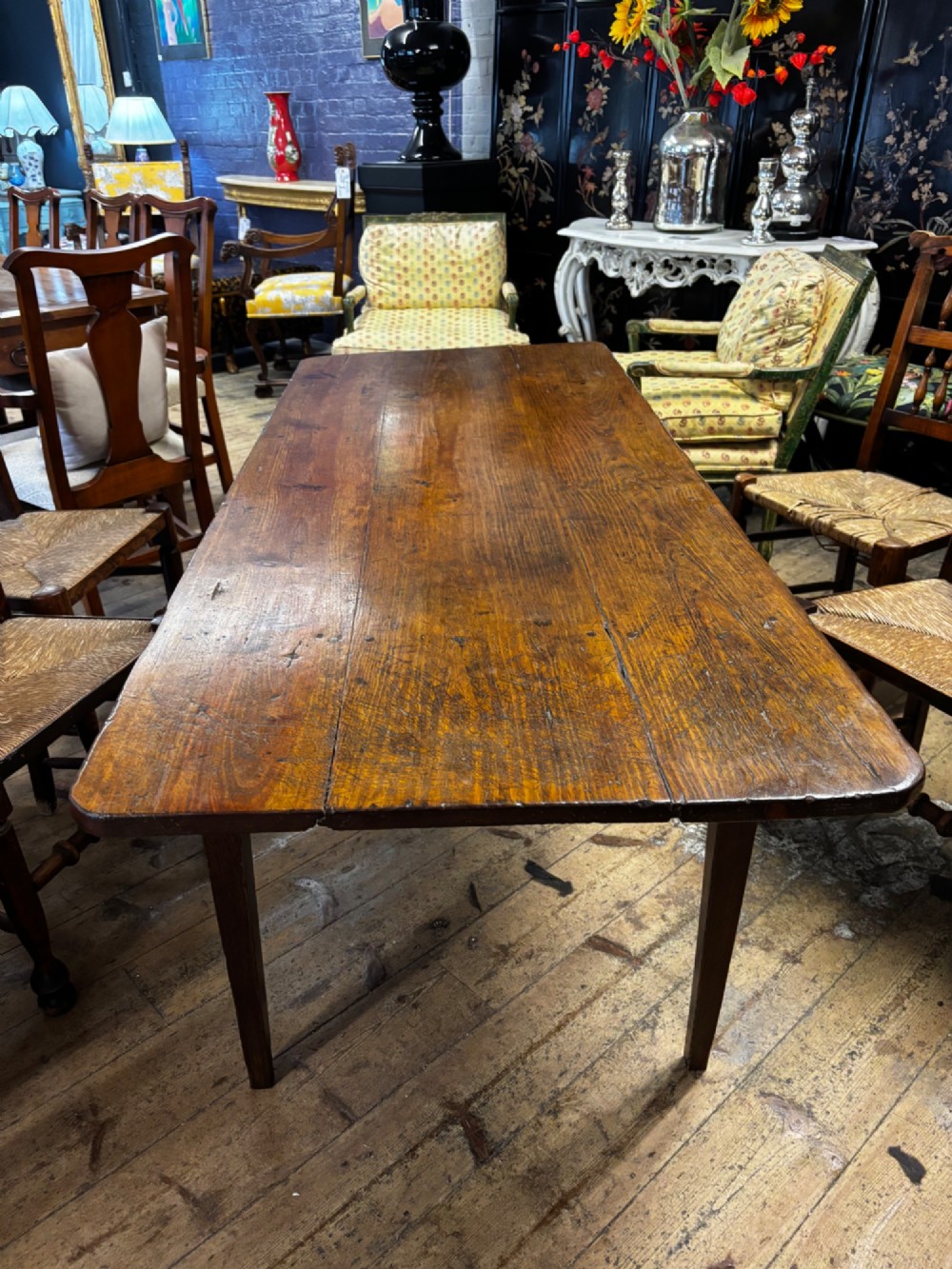 A late 19th-century rectangular fruitwood farmhouse dining table featuring a three-plank top and four square tapered legs.