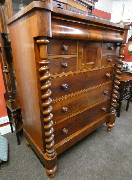 fig 1. A tall Victorian flame mahogany Scotch chest of drawers featuring spiral barley twist side columns, a central square drawer flanked by smaller drawers, and three long graduated drawers below.