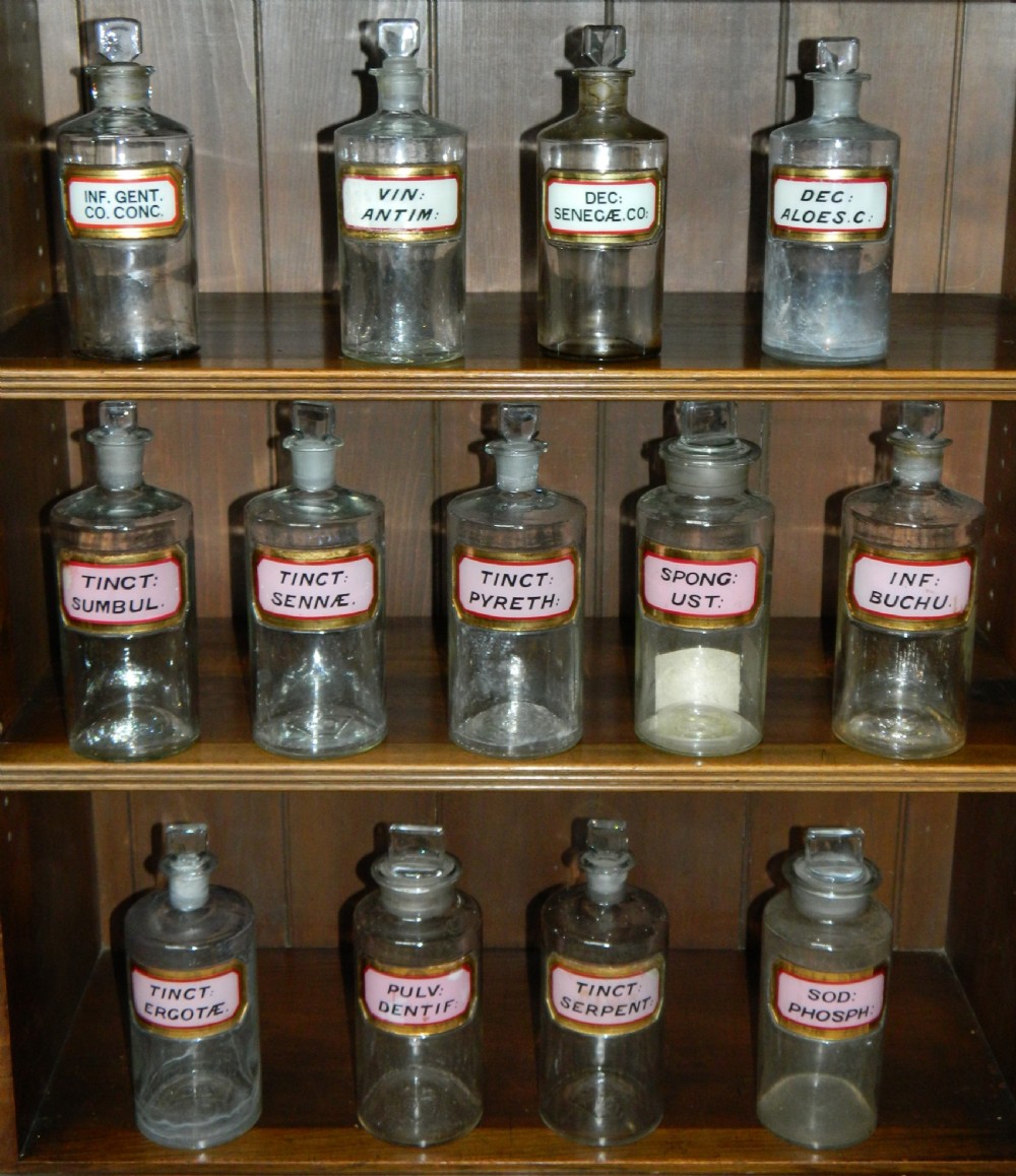 A set of twenty-nine clear glass Victorian apothecary jars with ground glass stoppers and gilt-bordered Latin paper labels. View III