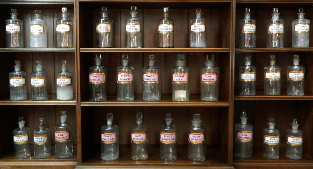 A set of twenty-nine clear glass Victorian apothecary jars with ground glass stoppers and gilt-bordered Latin paper labels. View VII