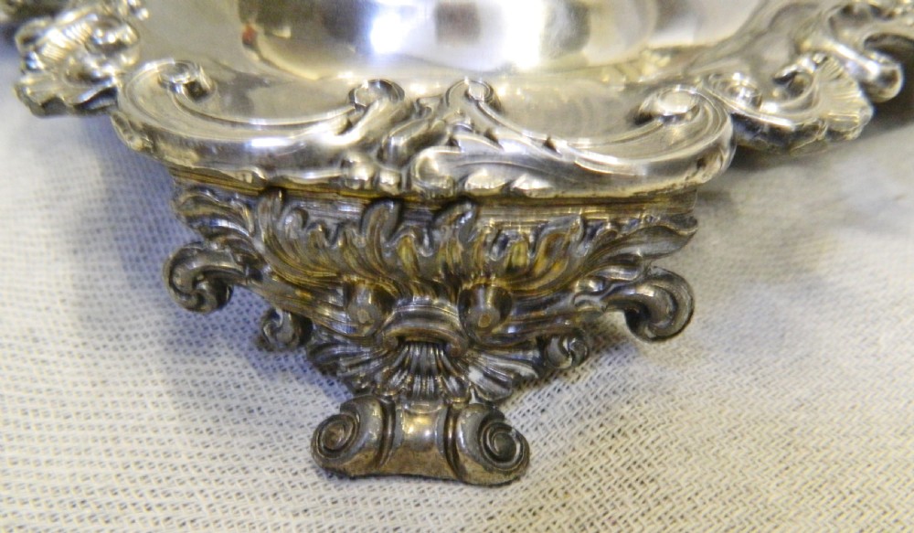 A Victorian silver-plated decanter stand featuring a central foliate handle and four matching cut-glass decanters with faceted stoppers. View III