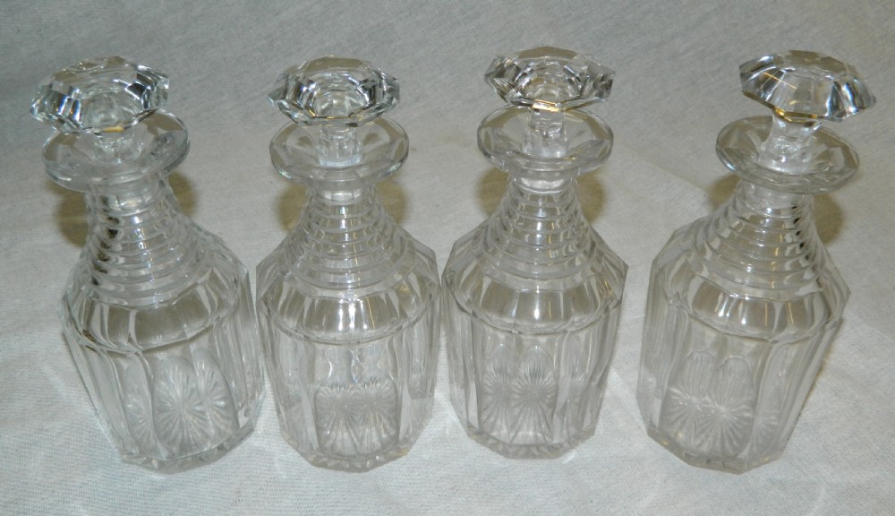 A Victorian silver-plated decanter stand featuring a central foliate handle and four matching cut-glass decanters with faceted stoppers. View VII