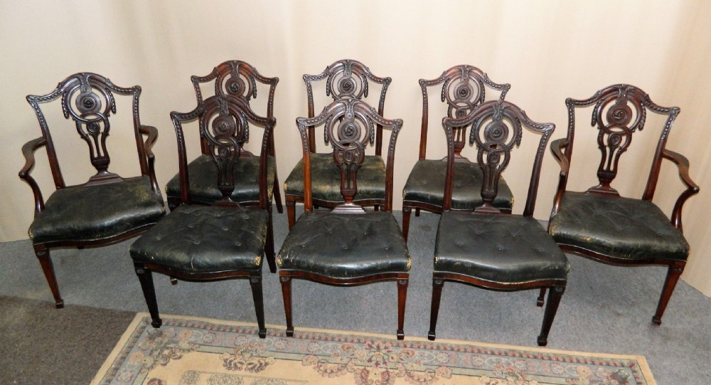 A set of eight dark mahogany dining chairs including six side chairs and two carver armchairs with intricate carved splat backs and buttoned dark leather seats. View II