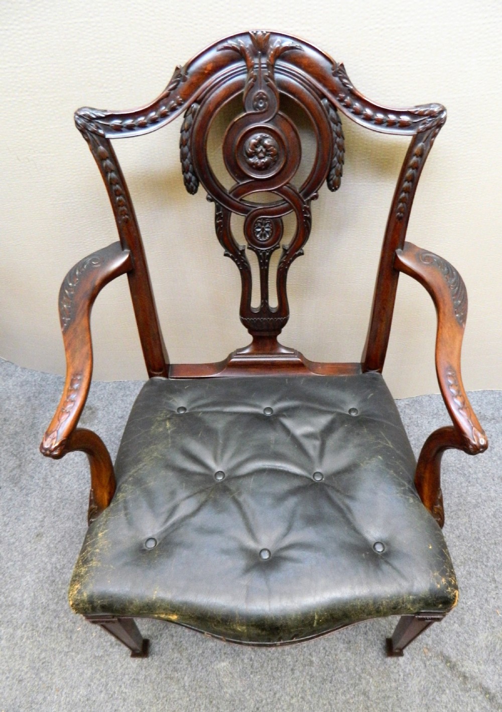 A set of eight dark mahogany dining chairs including six side chairs and two carver armchairs with intricate carved splat backs and buttoned dark leather seats. View V