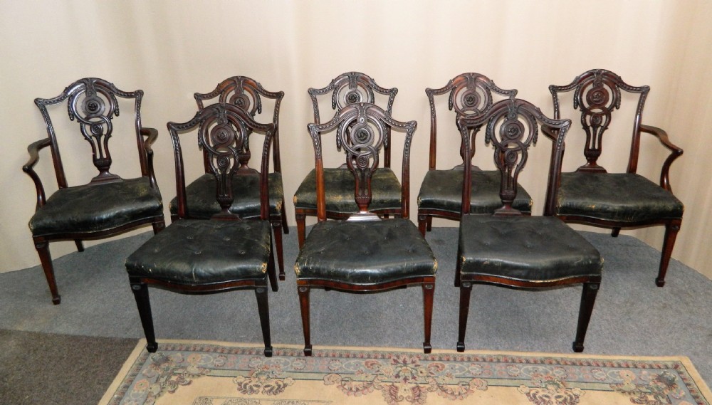 A set of eight dark mahogany dining chairs including six side chairs and two carver armchairs with intricate carved splat backs and buttoned dark leather seats. View VIII