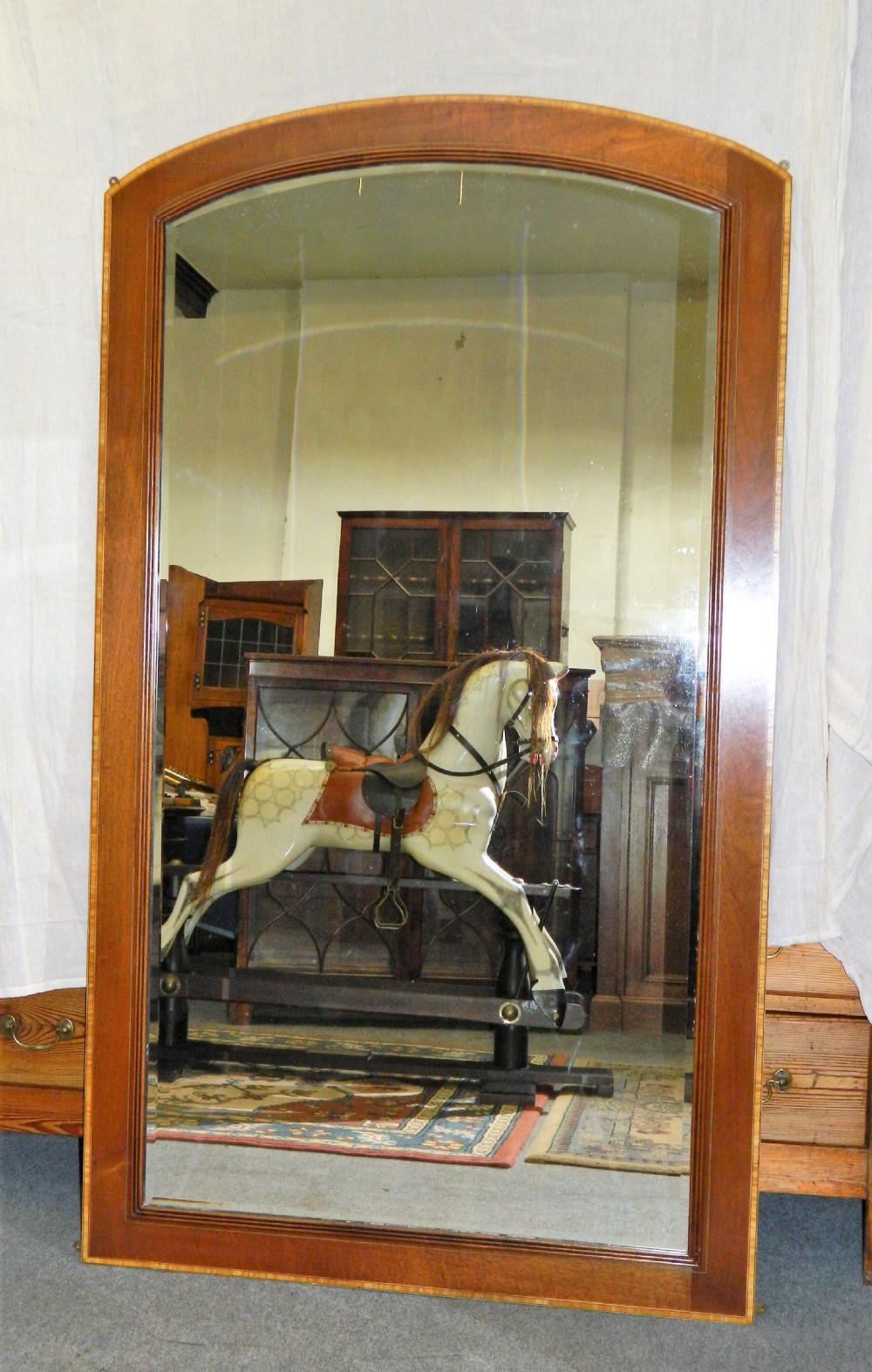 A large rectangular mirror with a gentle arched top set within a wide mahogany wood frame featuring contrasting satinwood crossbanding. View III