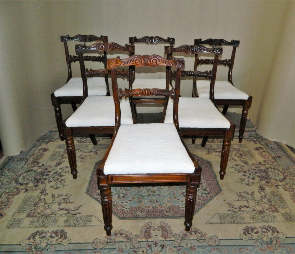 Set of six antique William IV rosewood dining chairs featuring carved scroll top rails and cream upholstered seats.