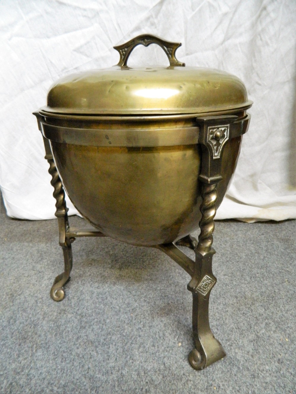 An Arts and Crafts period brass coal bin featuring a domed removable lid, top handle, and three twisted spiral legs on tripod feet. View IV