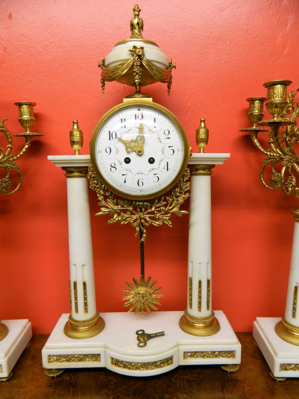 A French Neoclassical white marble and gilt ormolu portico mantel clock flanked by two matching five-light candelabra. View II