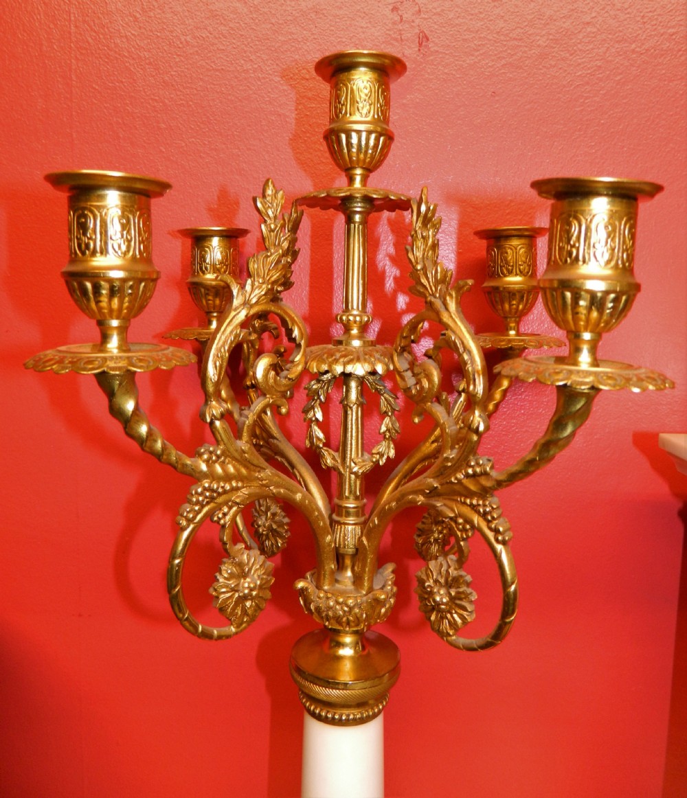A French Neoclassical white marble and gilt ormolu portico mantel clock flanked by two matching five-light candelabra. View VI