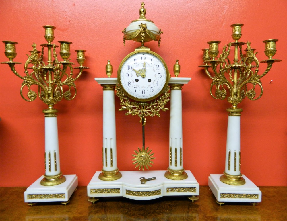 A French Neoclassical white marble and gilt ormolu portico mantel clock flanked by two matching five-light candelabra. View VIII