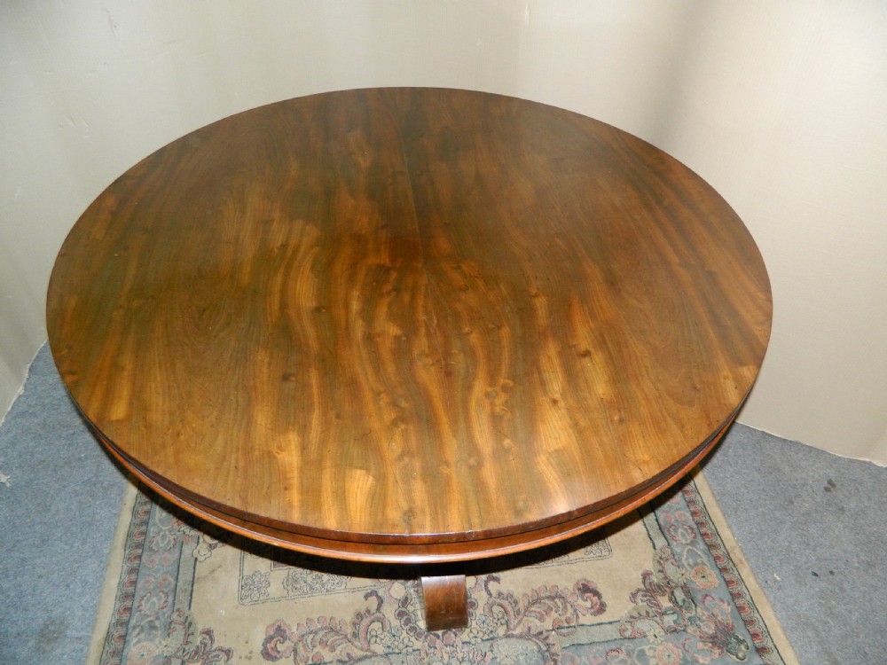 A large circular mahogany tilt-top table shown with its top tilted vertically above a curved pedestal base. View II