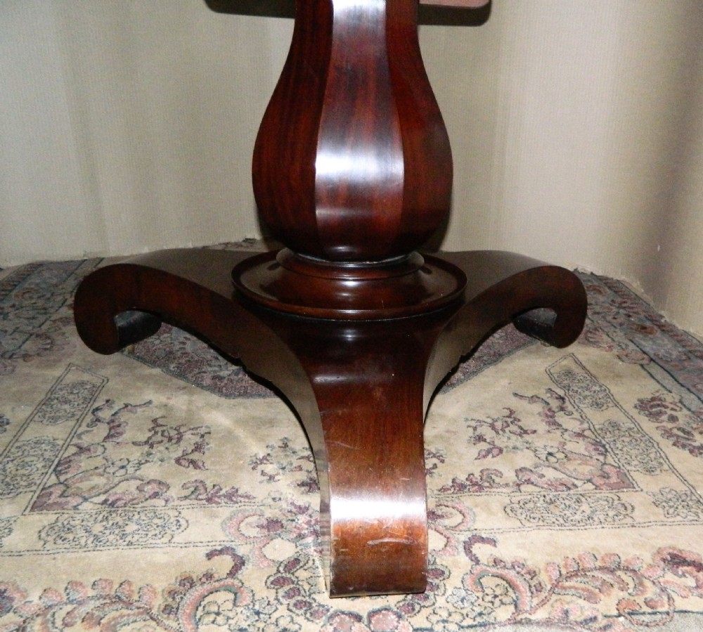 A large circular mahogany tilt-top table shown with its top tilted vertically above a curved pedestal base. View III