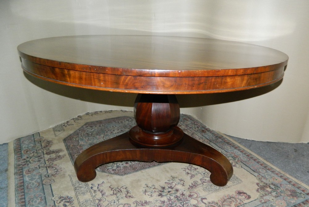 A large circular mahogany tilt-top table shown with its top tilted vertically above a curved pedestal base. View V