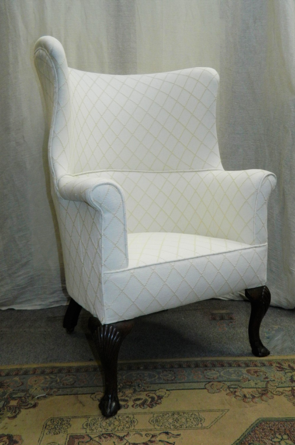 A Georgian barrel back armchair upholstered in a cream diamond-patterned fabric, supported by dark mahogany cabriole legs with shell-carved knees and ball and claw feet. View VI