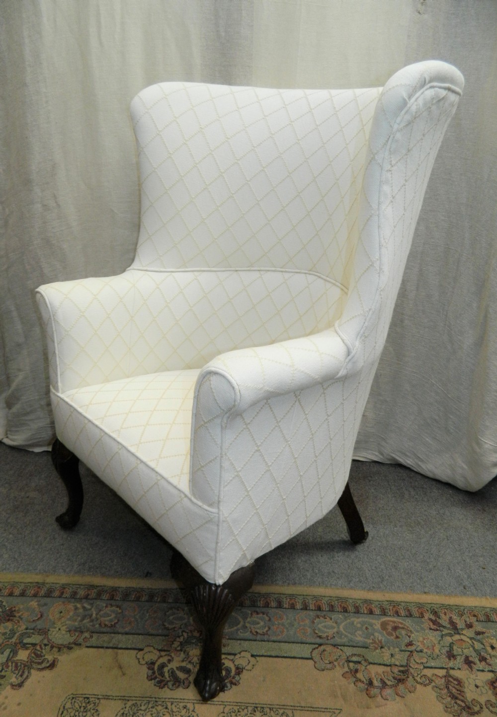 A Georgian barrel back armchair upholstered in a cream diamond-patterned fabric, supported by dark mahogany cabriole legs with shell-carved knees and ball and claw feet. View IX