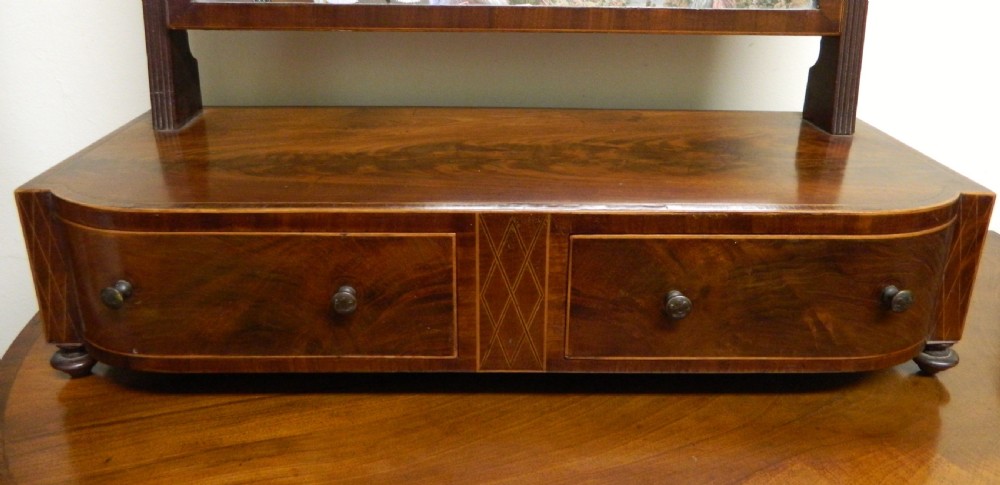 An antique mahogany toilet mirror featuring a swivelling arched glass frame mounted on a base with two inlaid drawers. View II
