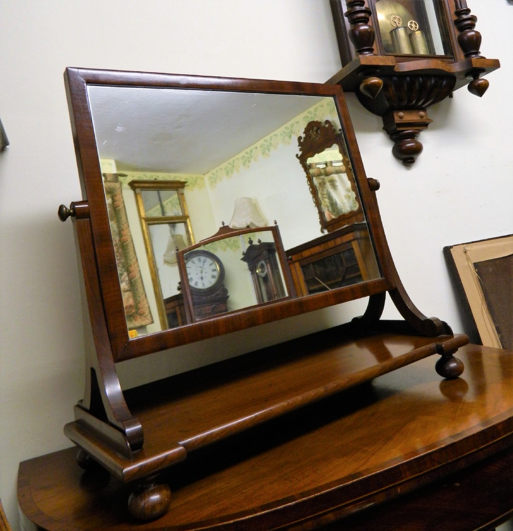 An antique mahogany rectangular toilet mirror supported on curved upright arms above a rectangular plinth base with bun feet. View III