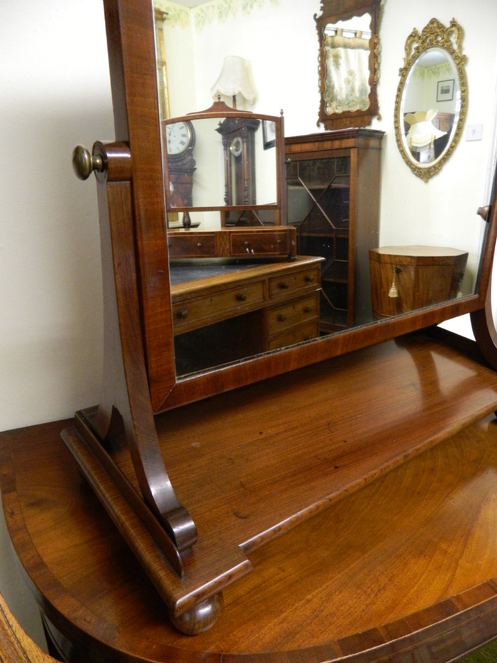 An antique mahogany rectangular toilet mirror supported on curved upright arms above a rectangular plinth base with bun feet. View IV
