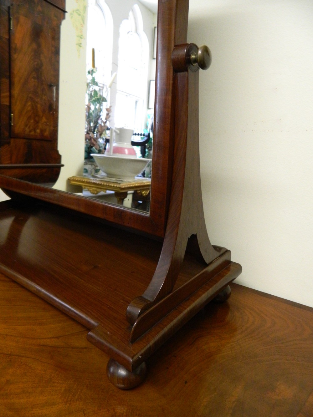 An antique mahogany rectangular toilet mirror supported on curved upright arms above a rectangular plinth base with bun feet. View V