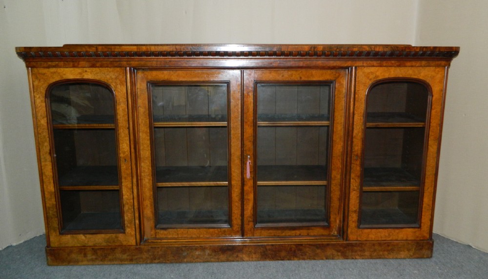 A large Victorian burr walnut bookcase featuring four glass-panelled doors, detailed wood grain patterning, and a solid plinth base. View II