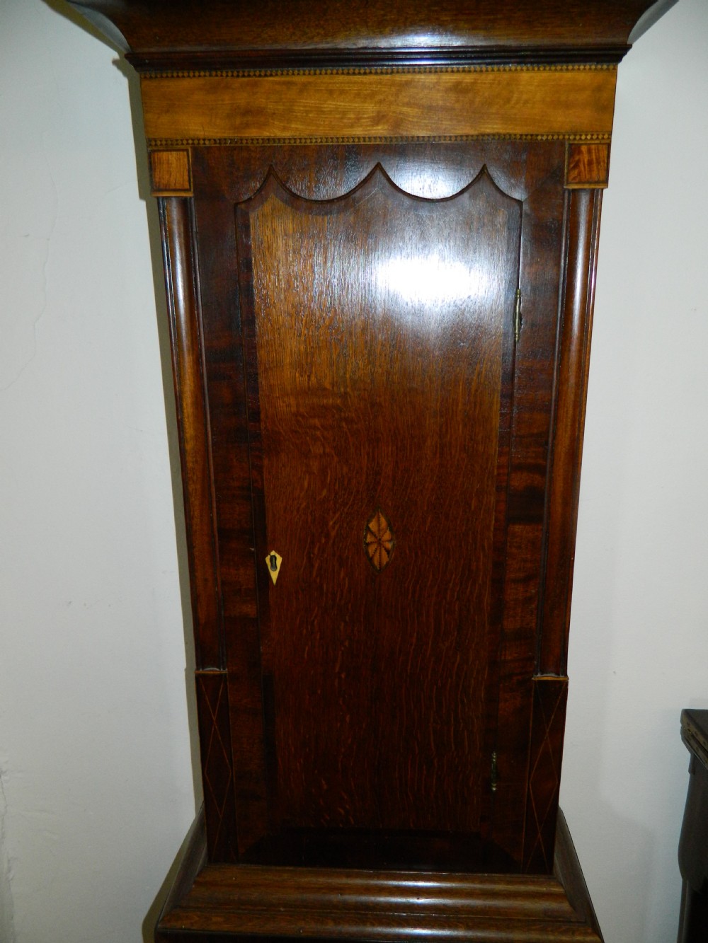 An antique Georgian mahogany longcase clock featuring a swan-neck pediment with brass finials, a painted arch dial, and string inlay details. View II
