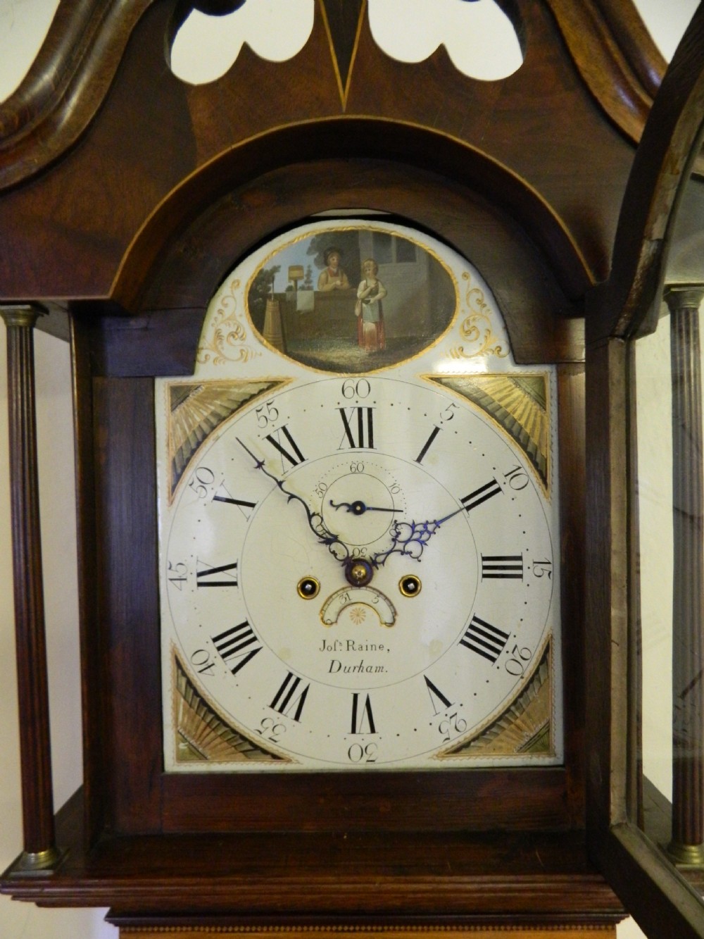 An antique Georgian mahogany longcase clock featuring a swan-neck pediment with brass finials, a painted arch dial, and string inlay details. View VIII