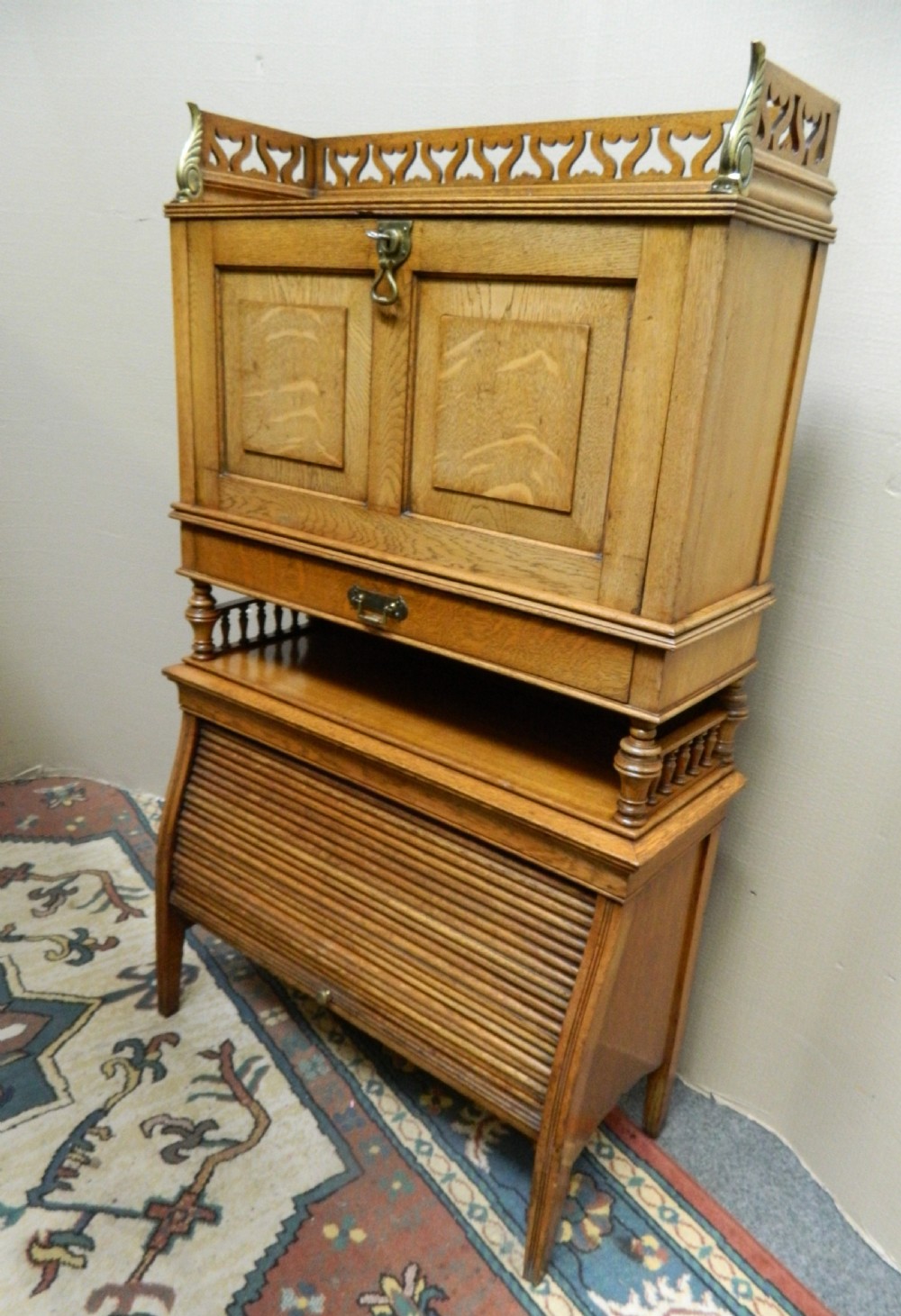 An Arts and Crafts golden oak bureau featuring a pierced heart gallery top, a fall-front writing section, a single drawer, an open spindle shelf, and a lower tambour front cabinet. View III
