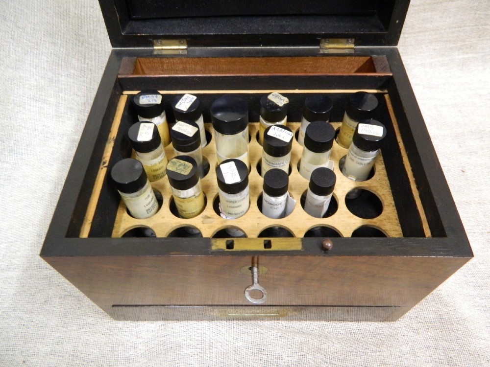 An opened Victorian mahogany apothecary chest displaying rows of glass medicine phials in fitted compartments and a lower drawer containing labelled bottles. View V